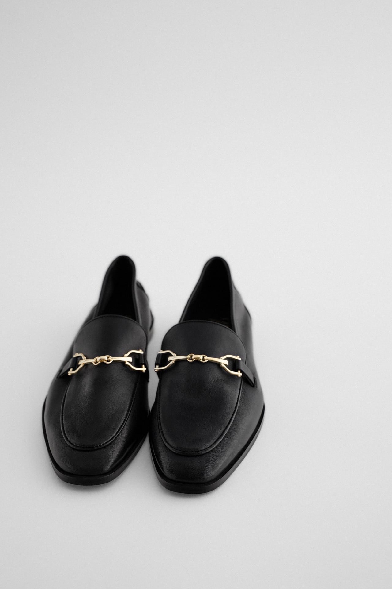 Zapato plano tipo mocasín negro de piel con hebilla en la parte delantera, de Zara (39,95€)