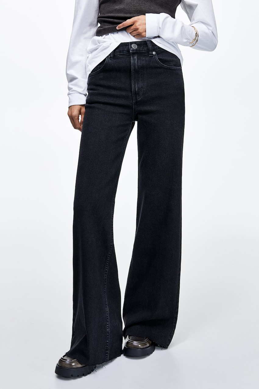 Jeans wide leg comfort de tiro medio con diseño de cinco bolsillos, cintura con trabillas, cierre de cremallera y botón, confeccionados en tejido elástico.