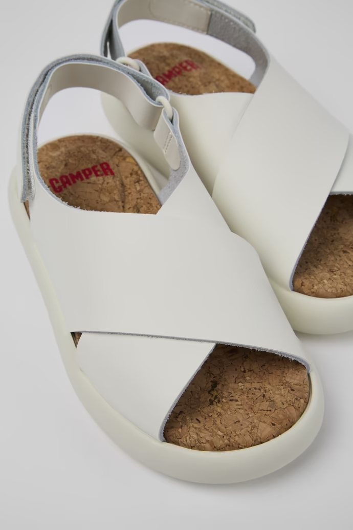 Sandalias de piel blancas con tira en X para niños, con sistema de autocierre y plantillas y suelas de EVA. Combinando volumen y simplicidad del diseño, cuenta con una suela de origen natural que proporciona bienestar y acolchado.