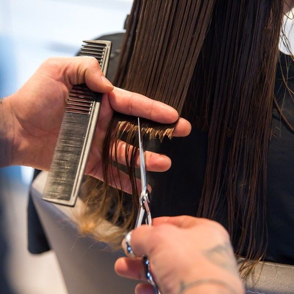 Chica cortándose las puntas del cabello.